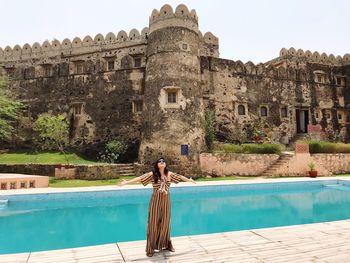 Woman with arms outstretched standing by swimming pool