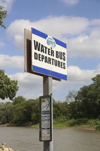 Information sign by road against sky