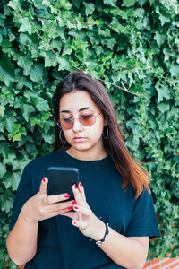Teenager looking at the mobile phone with sunglasses