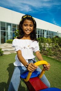 Portrait of smiling girl sitting on seesaw