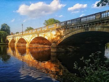 Arch bridge over river against sky