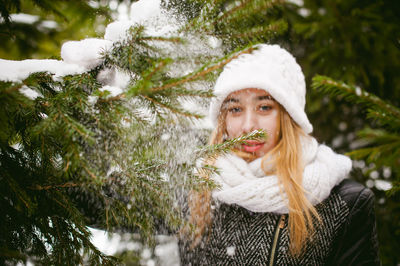 Young woman wearing warm clothing while standing by trees during winter