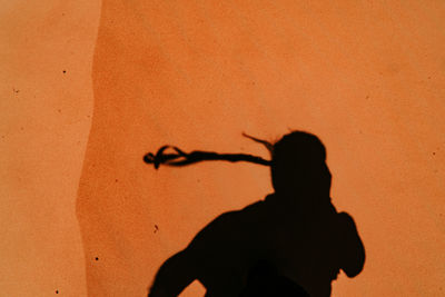Shadow of woman on orange wall