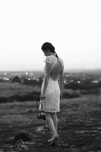 Young woman standing on field against clear sky