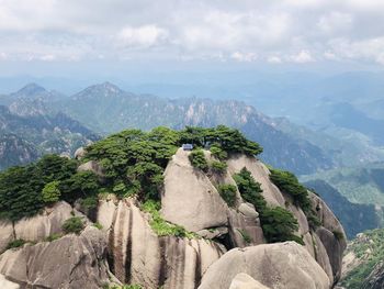 Rocks on mountain against cloudy sky