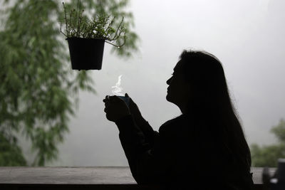 Side view of woman holding potted plant