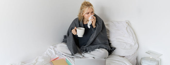 Portrait of young woman sitting on bed at home