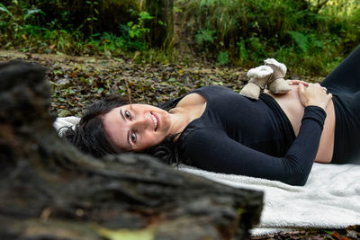 Portrait of smiling pregnant woman lying on picnic blanket