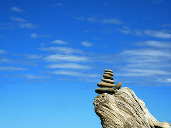 Low angle view of cairn stack against blue sky