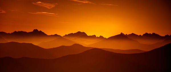 Scenic view of silhouette mountains against orange sky