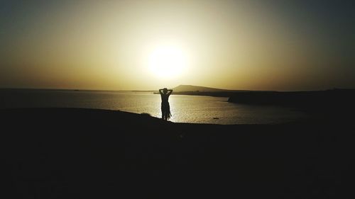 Silhouette person on beach against sky during sunset