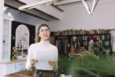 Portrait of young woman standing at home