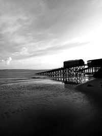 Pier on beach against sky
