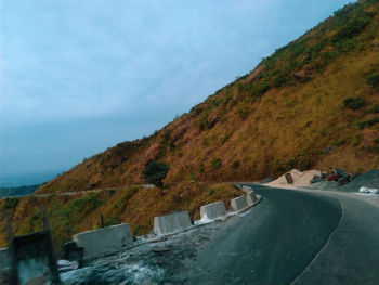 Scenic view of road amidst mountains against sky