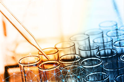 Digital composite image of liquid dripping from pipette into test tube with molecular structure