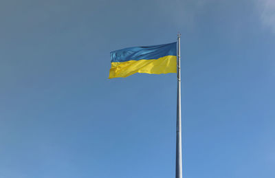 Low angle view of flag against clear blue sky