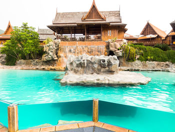 Swimming pool by built structure against sky