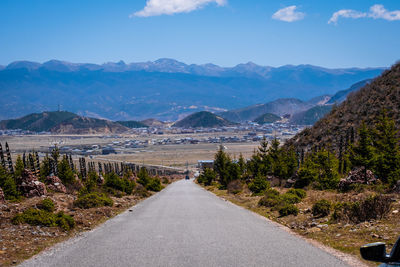 Road leading towards mountains against sky