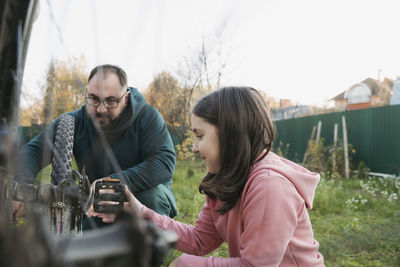 Father and daughter repairing bicycle together in back yard