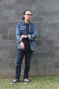 Full length portrait of young man standing against wall