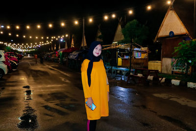 Woman standing on wet street at night