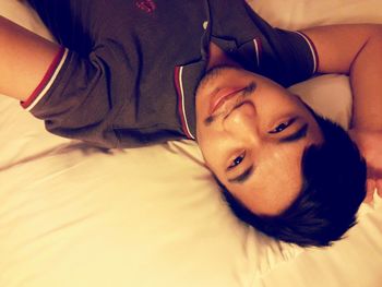 High angle portrait of boy lying on bed at home