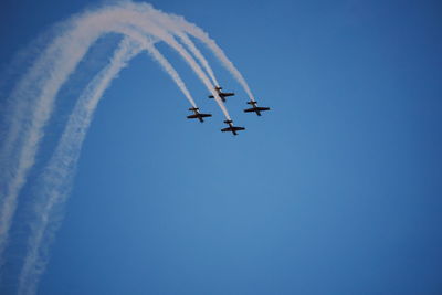 Low angle view of airshow against clear blue sky