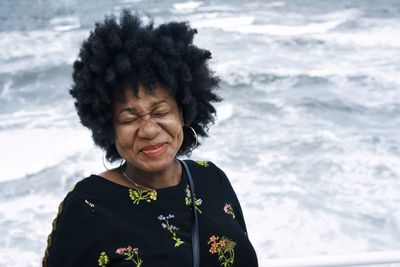 Close-up of smiling woman against sea