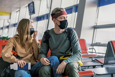 Couple of tourists are waiting for their flight at an empty airport during the pandemic. 