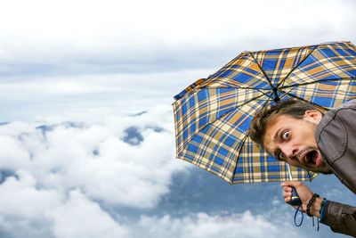 Man with mouth open against clouds