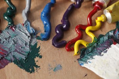 Close-up of colorful paints spilled from tubes on wooden table