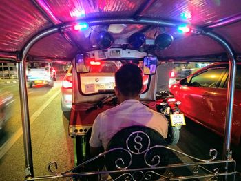 Rear view of man sitting in bus at night