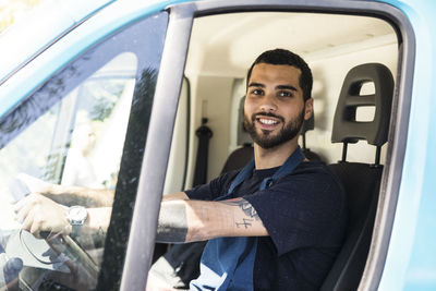 Portrait of confident young male owner driving food truck in city