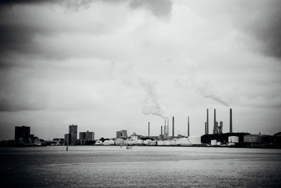 View of river and factory against sky