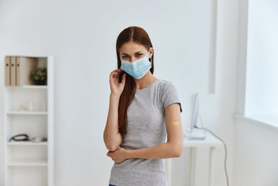 Portrait of woman wearing mask standing at hospital