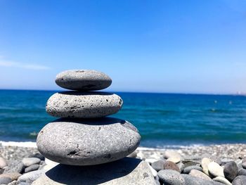 Close-up of stack of pebbles on beach against sky