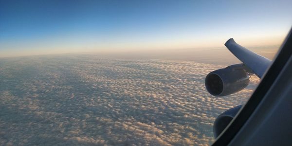 Close-up of airplane wing over landscape against sky