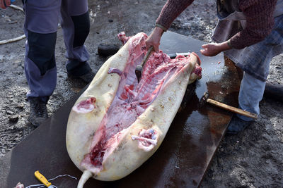 Low section of butchers cutting pork