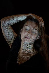 Close-up portrait of woman against black background