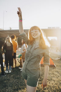 Happy young woman gesturing while standing on lawn