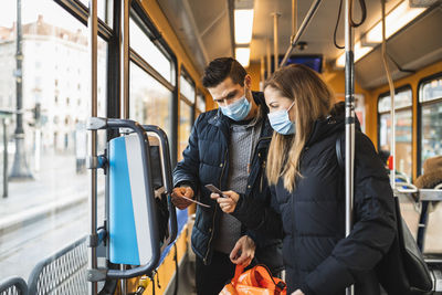 Heterosexual couple buying ticket in tram during pandemic