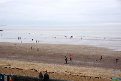 People playing at beach against sky