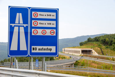 Information sign by road against sky