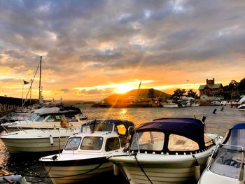 Boats moored at harbor against sky during sunset