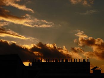 Low angle view of silhouette buildings against cloudy sky