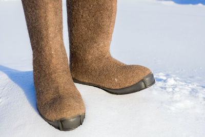 Rubber boots on snow covered field during sunny day