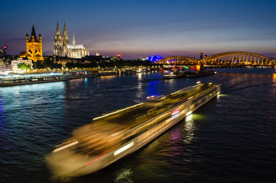 Illuminated city by river at night