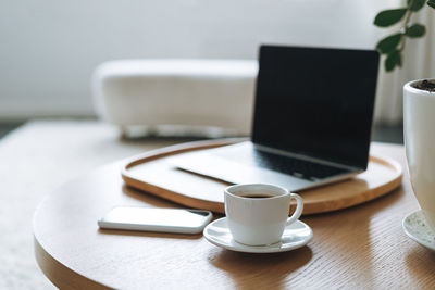 Working place with cup of coffee, open laptop on wooden table in office room, business interior