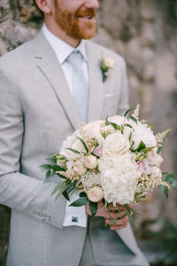 Midsection of man holding rose bouquet