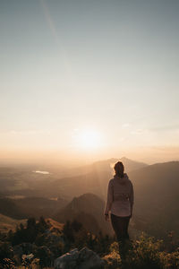 Rear view of man standing on mountain during sunset